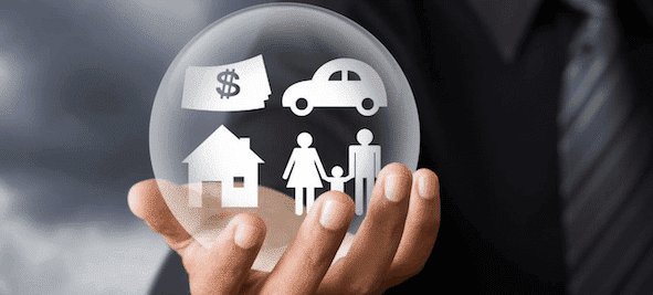 a hand holding a protective bubble around a house, car and money